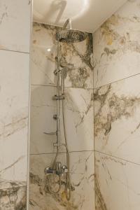 a shower in a bathroom with a marble wall at Meltemi Beach Apartments 2 in Milatos +46 photos