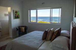 a bedroom with a bed with a view of the ocean at Seafront house with a view in Kleinmond