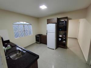 a kitchen with a white refrigerator and a sink at Casa Marco in Anápolis