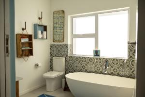 a bathroom with a tub and a toilet and a window at Seafront house with a view in Kleinmond +56 photos