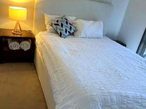 a bedroom with a white bed with a lamp and towels at Oak Hill Cottage - Chirnside Park in Wonga Park
