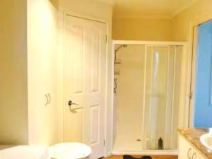 a bathroom with a shower and a white door at Oak Hill Cottage - Chirnside Park in Wonga Park +7 photos