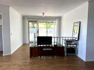 an empty living room with a television and a desk at Oak Hill Cottage - Chirnside Park in Wonga Park