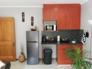 a kitchen with a stainless steel refrigerator and wooden cabinets at The Boho Suite in Benoni