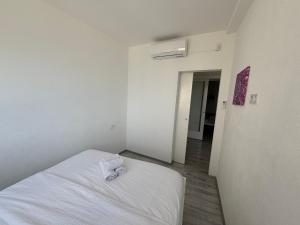 a bedroom with a white bed with a towel on it at Apartman Cezar2 in Rogoznica