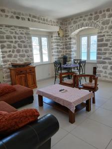 a living room with tables and chairs and a stone wall at Palate Verona in Prčanj