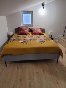 a bedroom with a bed with a yellow blanket and red pillows at Le petit chalet in Mazaye
