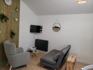 a living room with a couch and a tv at Le petit chalet in Mazaye