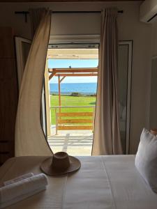 a hat on a bed with a view of the ocean at Cedrus-Seafront Ionian Stay in Agios Georgios