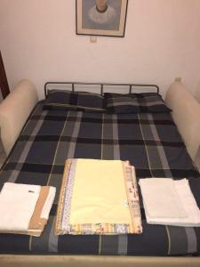 a bed with checked sheets and towels on it at Airy and cosy summer flat in Siviri