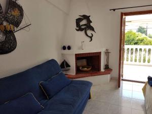 a living room with a blue couch and a fireplace at Airy and cosy summer flat in Siviri
