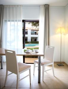 a dining room with a table and chairs and a window at Sagres Time Apartamentos in Sagres