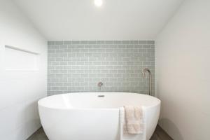 a white bath tub in a bathroom with a brick wall at Connewarre Farm Stay - Sleeps 10 - Acreage By HostyCo in Connewarre +25 photos