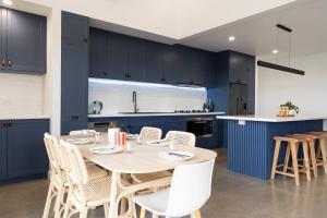 a kitchen with blue cabinets and a table and chairs at Connewarre Farm Stay - Sleeps 10 - Acreage By HostyCo in Connewarre