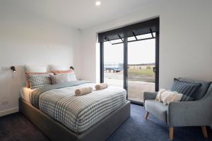 a bedroom with a bed and a chair and a window at Connewarre Farm Stay - Sleeps 10 - Acreage By HostyCo in Connewarre