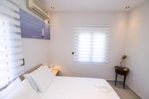 a white bedroom with a bed and a window at Villa Laurela in Salamina