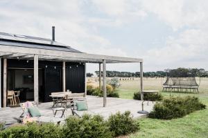 a wooden deck with chairs and tables in a field at Connewarre Farm Stay - Sleeps 10 - Acreage By HostyCo in Connewarre