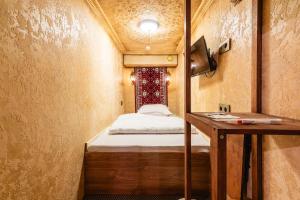 a small room with a bed and a table at Alladin Capsule Hotel in Almaty