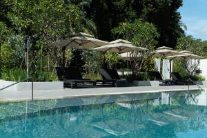 a swimming pool with umbrellas and chairs next to a swimming pool at The Initial Sama Serviced Residences in Singapore