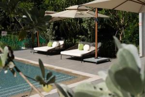 a pool with two lounge chairs and an umbrella at The Initial Sama Serviced Residences in Singapore