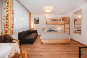 a bedroom with a bed and a couch and bunk beds at Landhaus Gerstgraser in Rauris