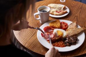 a table with a plate of breakfast food and a cup of coffee at The Longshoot in Nuneaton +24 photos