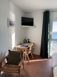 a living room with a table and a tv on the wall at Atlantic Hôtel - L'Ile d'Yeu in L'Ile d'Yeu