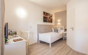 a white bedroom with a bed and a desk at REGIOHOTEL Wolmirstedter Hof in Wolmirstedt