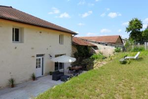 an external view of a house with a table and an umbrella at Graine in Dommartin-le-Franc
