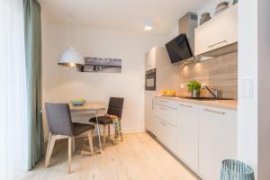a kitchen with white cabinets and a table with chairs at Am Park 27 in Prerow