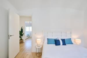 a bedroom with a white bed with blue pillows at CASA CALMA Blanes in Blanes