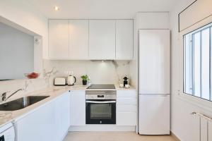 a white kitchen with a sink and a refrigerator at CASA CALMA Blanes in Blanes