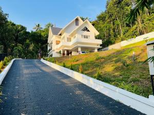 a house on a hill next to a road at Trinity Villa Home Stay in Idukki +50 photos