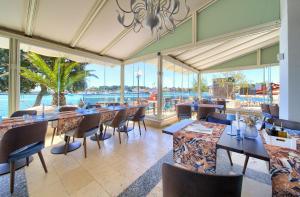 a restaurant with tables and chairs and a view of the water at Hotel Marina in Krk