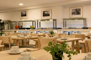 a restaurant with tables and chairs and a kitchen at Muthu La Perla Tenerife in Puerto de la Cruz