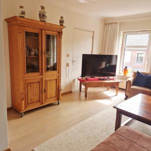 a living room with a large television and a wooden cabinet at B&B Chez Paz in Neer