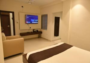 a bedroom with a bed and a chair and a television at Hotel Abhilasha Premium in Dewās +14 photos