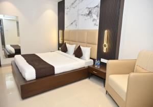 a bedroom with a bed and a couch and a chair at Hotel Abhilasha Premium in Dewās