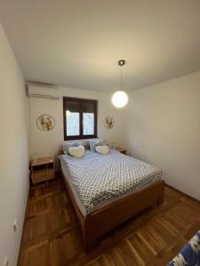 a bedroom with a bed with two pillows and a window at Plavi apartman Airport in Belgrade