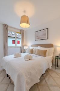 a white bedroom with a large bed with white sheets at Copper Suite · Seebach in Zurich
