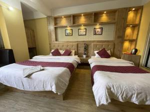 two beds in a hotel room with white and red pillows at Hotel Sambridhi in Panepa