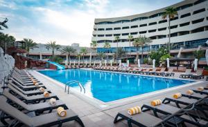 a swimming pool with lounge chairs and a hotel at Occidental Sharjah Grand in Sharjah +52 photos