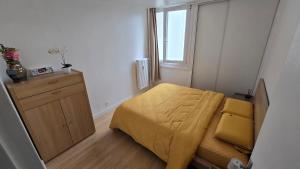 a small bedroom with a bed with a yellow blanket at Appartement proche Lille in Mons-en-Baroeul