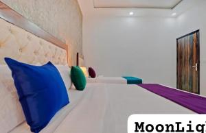 a bedroom with a bed with blue and green pillows at The MoonLight Hotel in Zirakpur +5 photos
