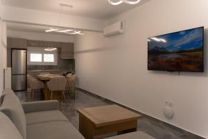 a living room with a couch and a tv on a wall at MARRONI RETREAT - Pool - Spa - Gym in Skotina