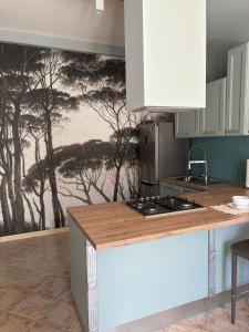 a kitchen with a painting of trees on the wall at Appartamento Accogliente tra Borghi e Natura in Castelluccio dei Sauri +8 photos
