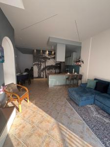 a living room with a blue couch and a kitchen at Appartamento Accogliente tra Borghi e Natura in Castelluccio dei Sauri
