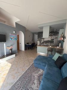 a living room with a blue couch and a kitchen at Appartamento Accogliente tra Borghi e Natura in Castelluccio dei Sauri