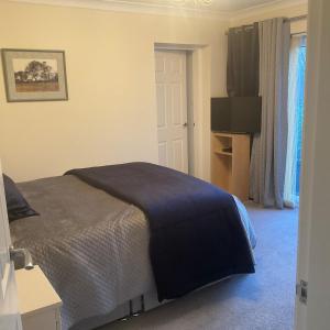 a bedroom with a bed and a flat screen tv at Cheshire 1 bedroom apartment - minimum 3 night stay please - garden view in Cheadle Hulme