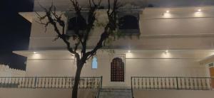 a white building with a tree in front of it at Tej Gadh Jambuda in Sālūmbar